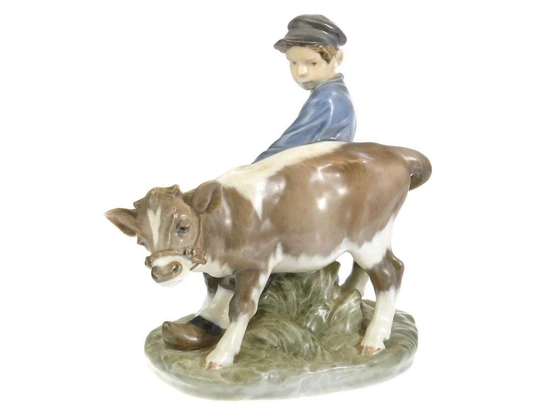 FIGURIN, pojke och kalv, Christian Thomsen, Royal Copenhagen, Danmark, nummer 772, längd ca 16 cm, höjd ca 17 cm. — Keramik/Figuriner — Kaplans
