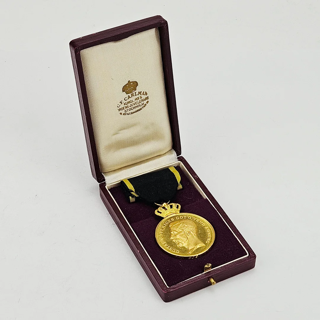 FÖRTJÄNSTMEDALJ, guld, 18-23K, Gustaf V, Sverige 1947, vikt inklusive band ca. 35 gram. — Orders & Medals — Auktionshuset Thörner & Ek