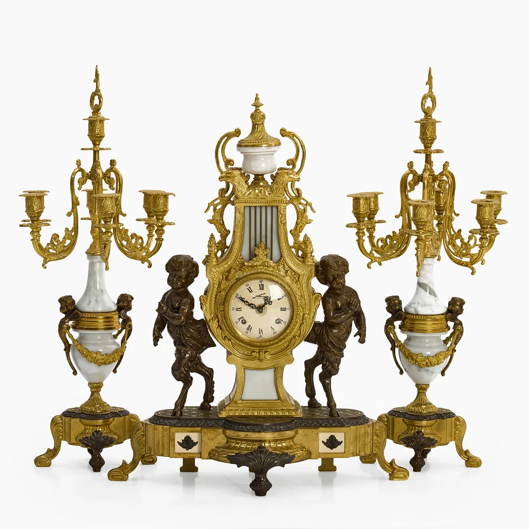 BORDSGARNITYR, 3 delar, Pendyl samt Kandelabrar. Förgylld och patinerad mässing samt marmor, dekor av fauner. 1900-talets mitt/andra hälft. — Candlesticks — Crafoord Auktioner Stockholm
