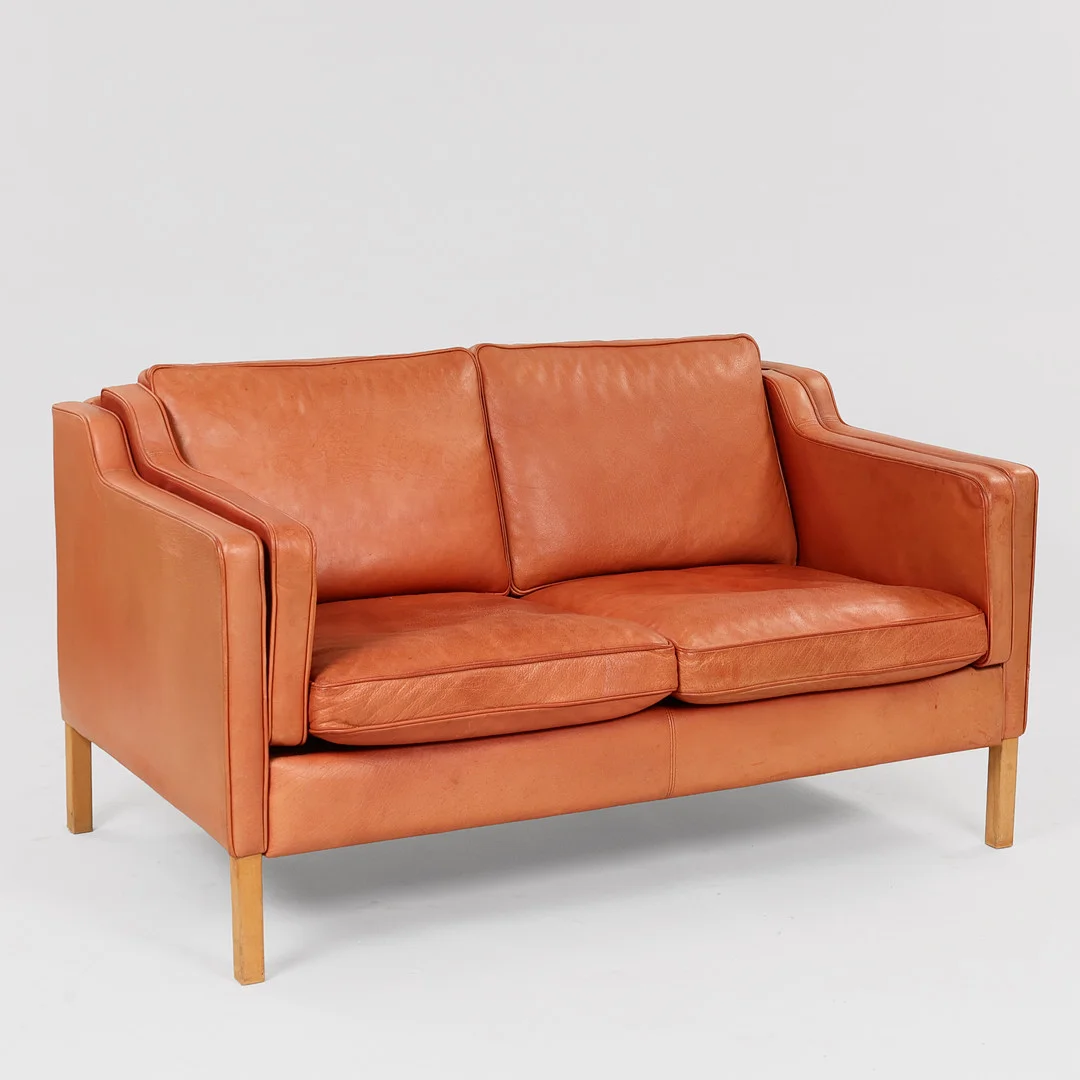 STOUBY. "Eva", topersoners sofa med ben af bøg, sæde, ryg og løse hynder betrukket med brunt skind, Danmark, 1900-tallets anden halvdel. — Sofas & Seatings — Palsgaard Kunstauktioner