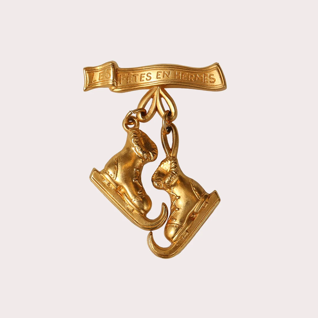 FÖRGYLLD BROSCH MED SKRIDSKOR, "Les Fêtes en Hermès". — Brooches & Pendants — Limhamns Auktionsbyrå