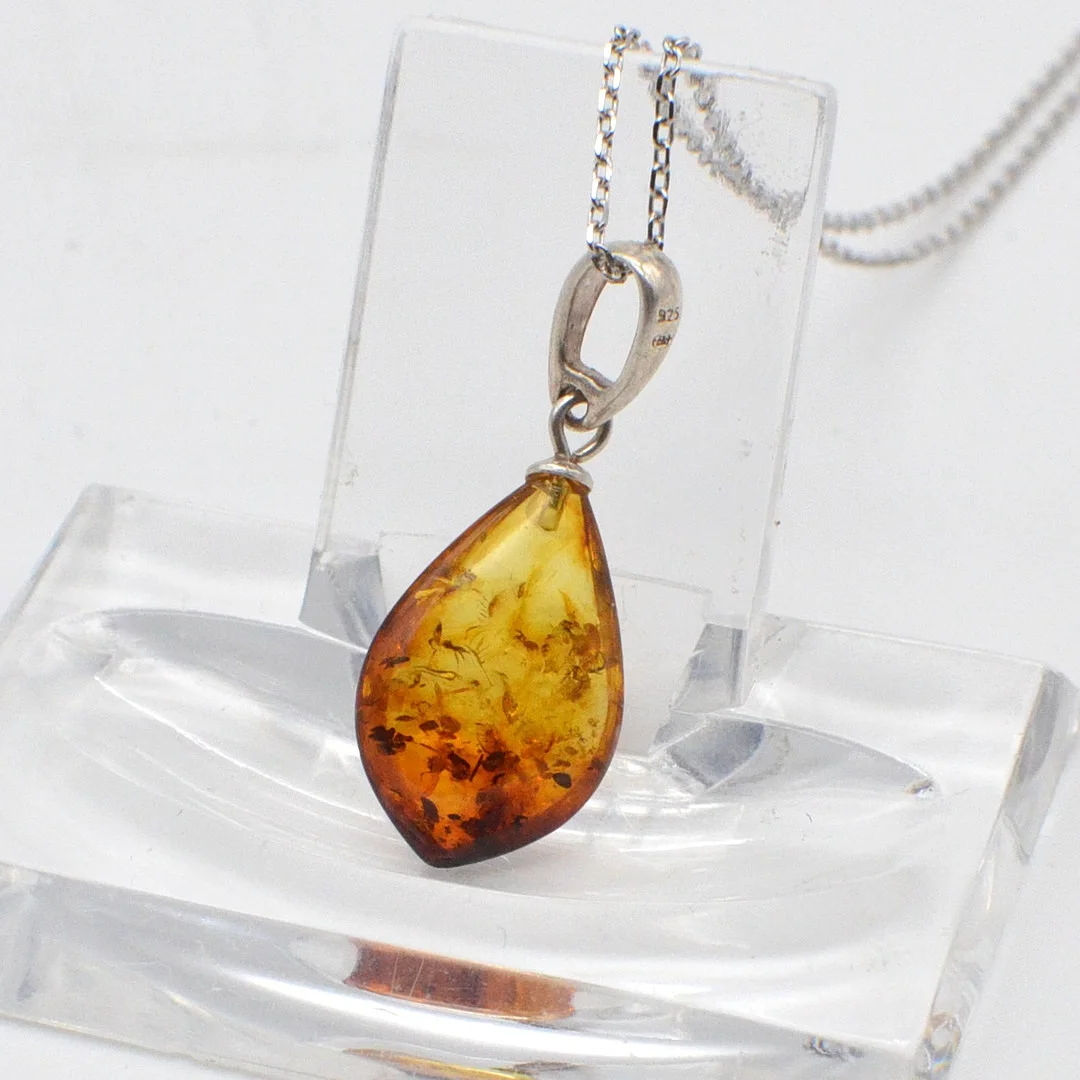 DESIGNERCOLLIER MIT EINEM BERNSTEIN-ANHÄNGER MIT BLATTEINSCHLÜSSEN, TROPFENFÖRMIG UND POLIERT, ANKERKETTE AUS STERLINGSILBER, STUDIOSTEMPEL "BB", VINTAGE. — Necklace — Kunst- und Auktionshaus Kleinhenz