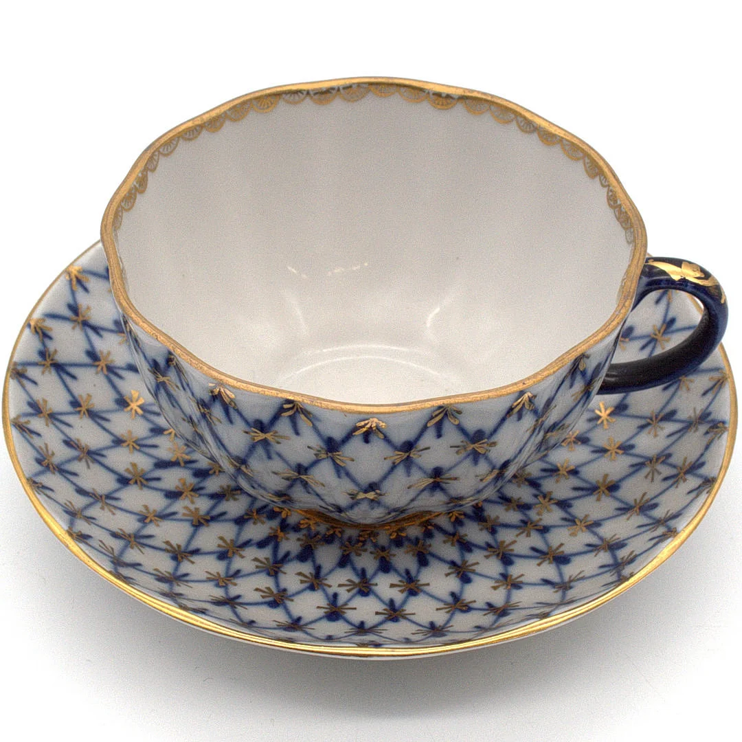 KAISERLICHE PORZELLANMANUFAKTUR LOMONOSSOW. „KOBALTNETZ“ TASSE SOWIE UNTERTASSE, HANDBEMALT KOBALTBLAU MIT GOLDENEN AKZENTEN. RUSSLAND 20. JAHRHUNDERT. — Rest of the world — Kunst- und Auktionshaus Kleinhenz