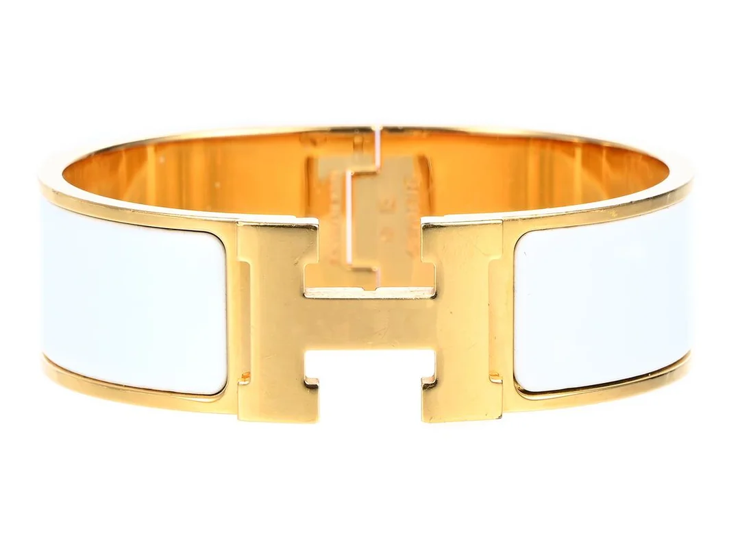 HERMÈS, ARMRING, Clic Clac H Bracelet, vit emalj, guldfärgade beslag, bredd 2 cm, diameter 5,5 cm, repor. Good Condition. — Smycken/Armring — Kaplans
